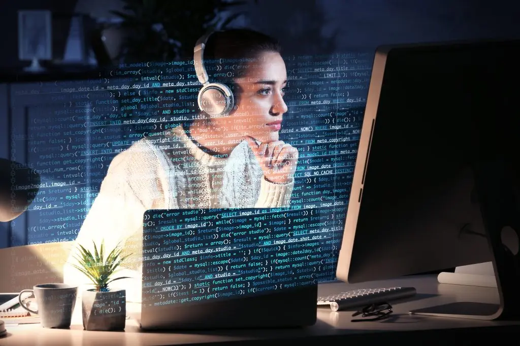 A woman wearing headphones and looking at a computer screen.