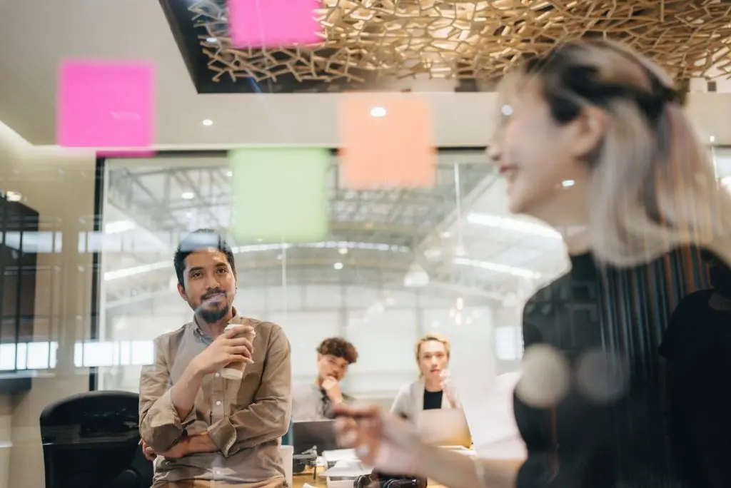 A group of people in an office with sticky notes on the wall.