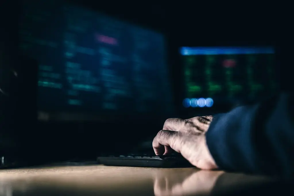 A person typing on a computer in the dark.
