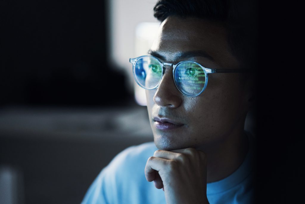Un homme avec des lunettes regardant un écran d'ordinateur.