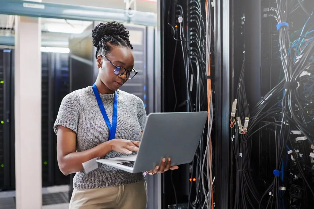 Femme utilisant un ordinateur portable dans une salle de serveurs