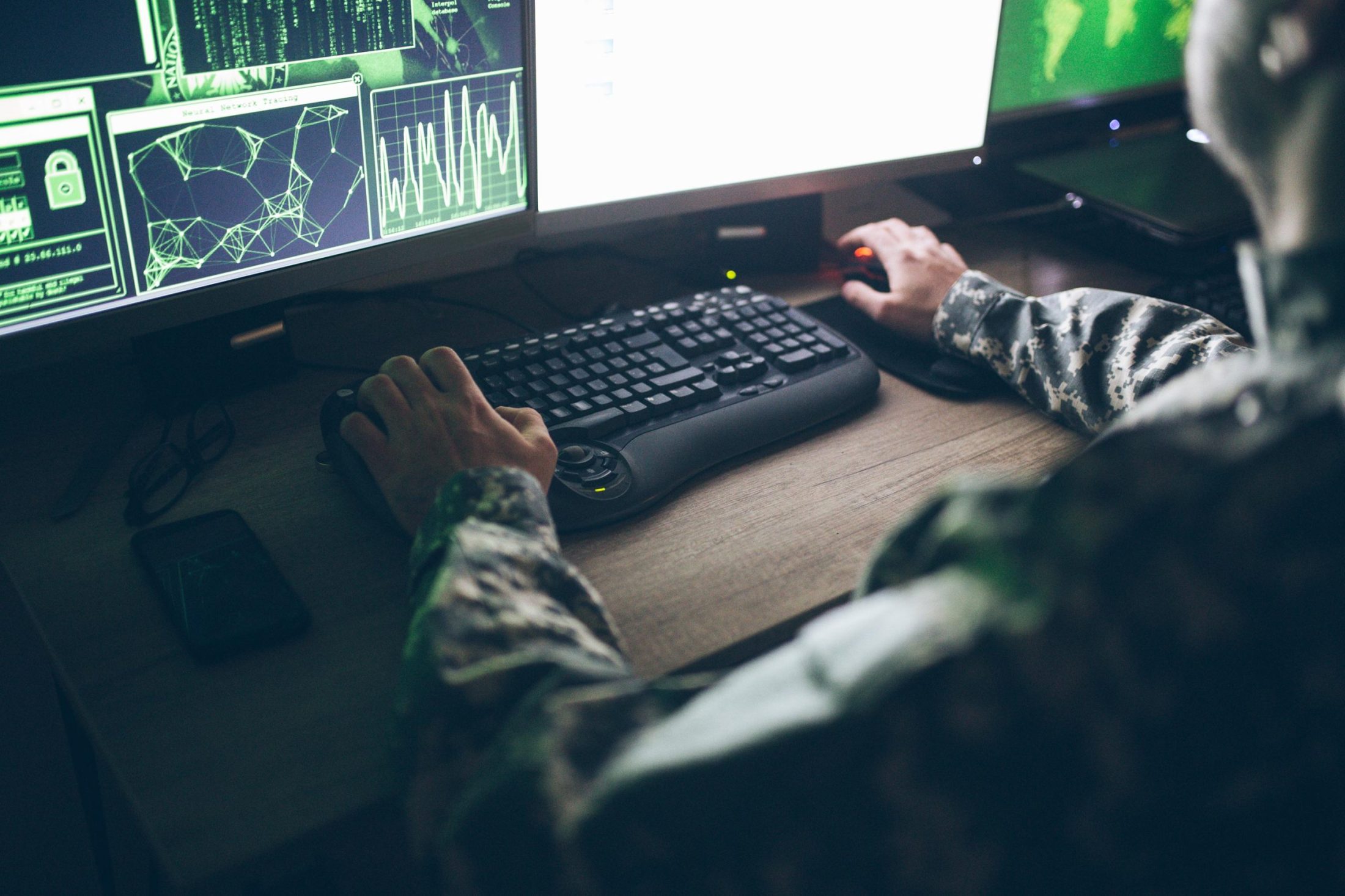 A man in camouflage is working on a computer.