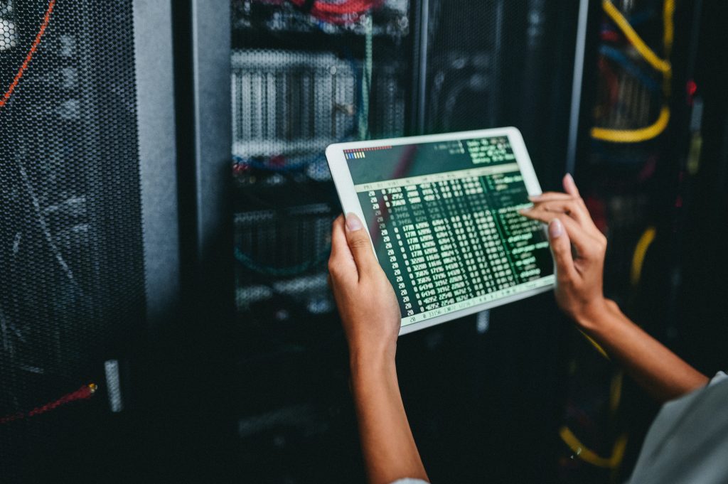 A person using a tablet in a server room.