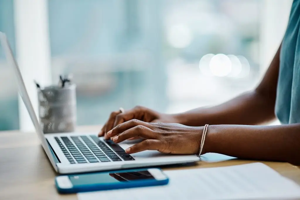 A woman typing on a laptop at a desk.