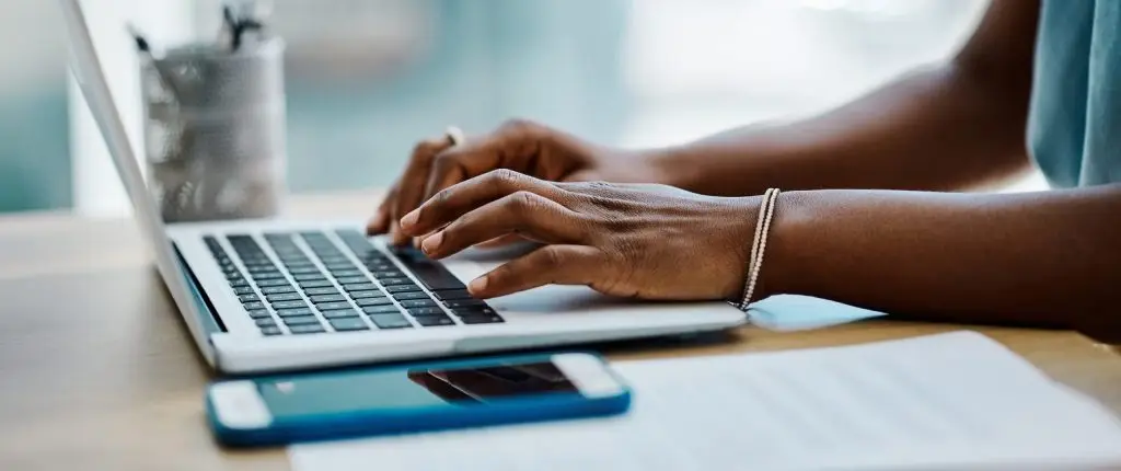 A woman typing on a laptop at a desk.