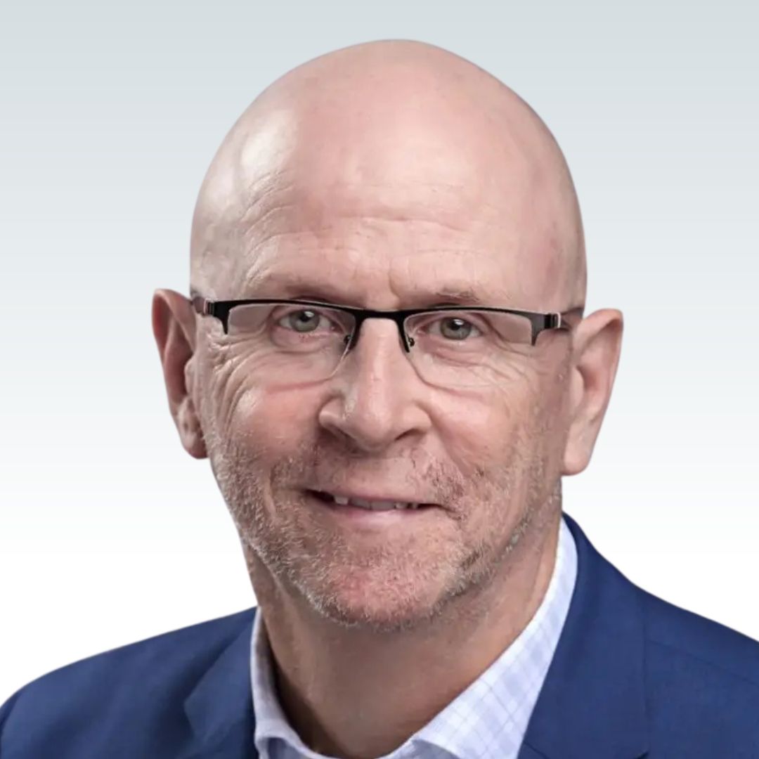 Kevin Ford, Calian CEO, with glasses wearing a blue suit and white shirt, smiling slightly against a light gray background.