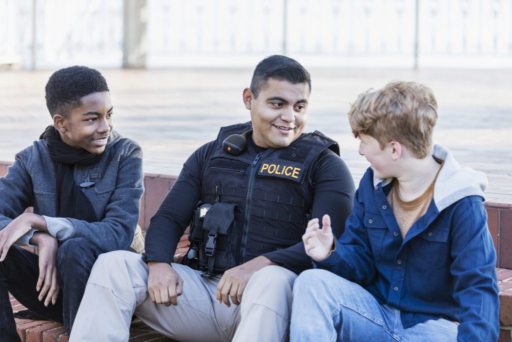 Police officer in community, sitting with two youths