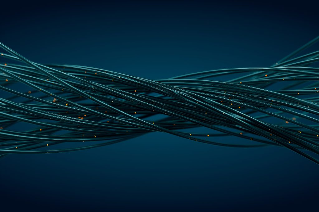 Abstract image of intertwined dark blue cables with small glowing orange lights, symbolizing connectivity or technology, set against a deep blue background.