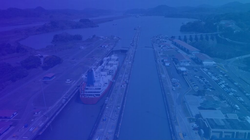 A large ship passes through a lock in the Panama Canal, surrounded by water and greenery.