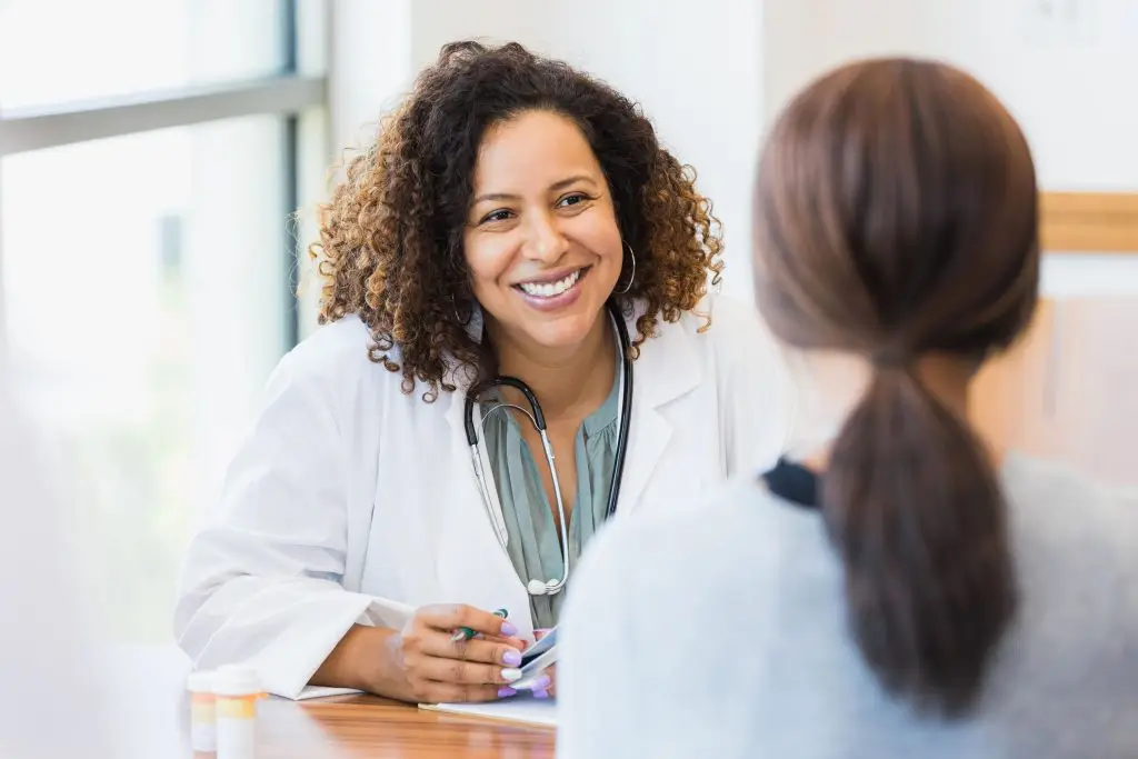 A doctor sitting down at a table, having a friendly conversation with a patient.