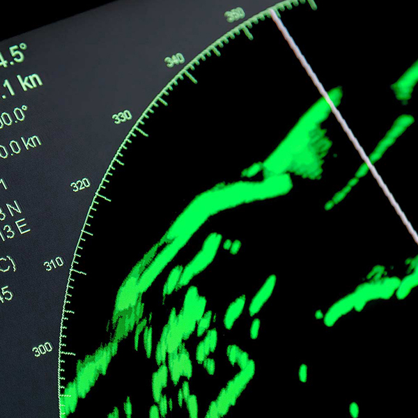 Close-up of a radar display showing green signal patterns and white grid lines on a dark screen, with numerical data in the top-left corner.