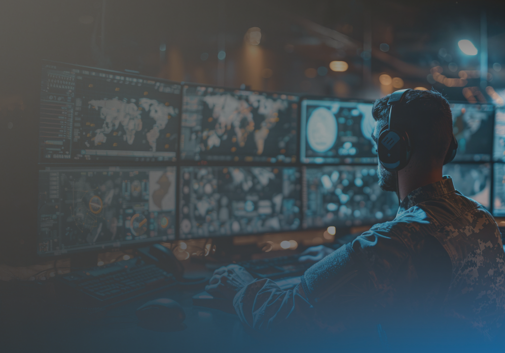 Person in military uniform wearing headphones monitors multiple world maps and data screens in a dark control room.