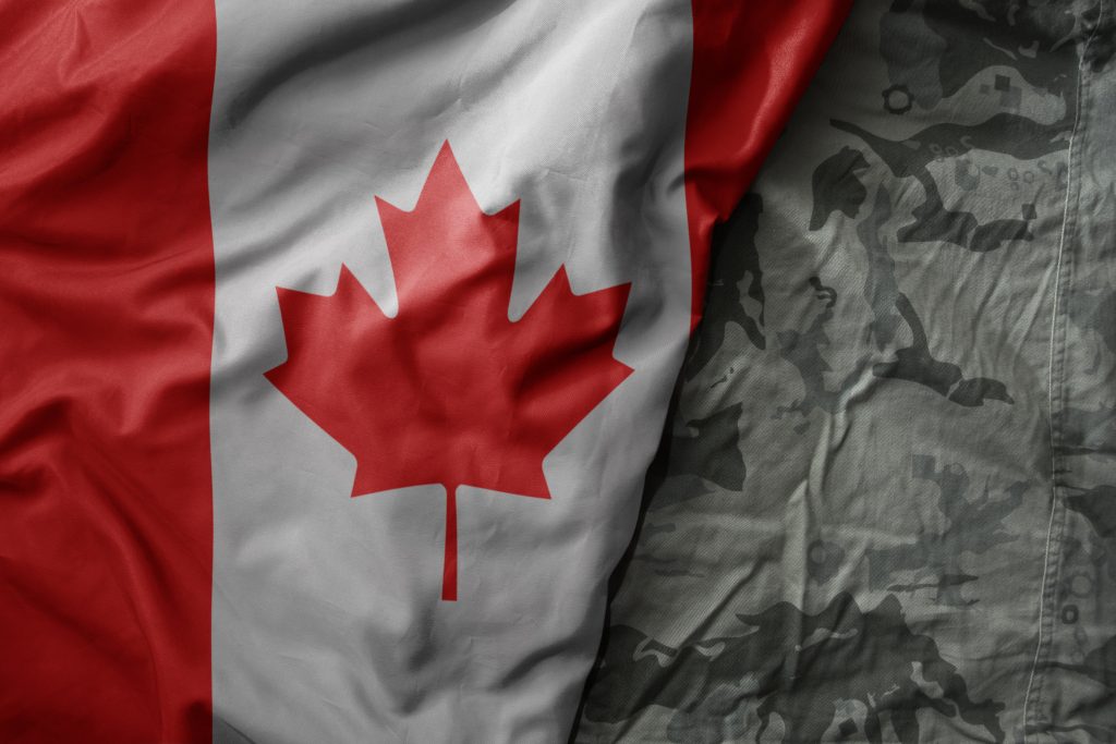 A Canadian flag is partially draped over a camouflage military uniform.