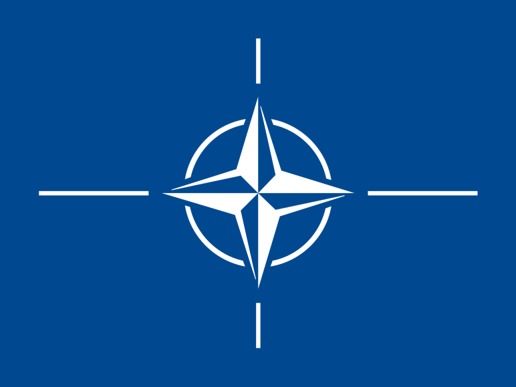 NATO flag featuring a white compass rose emblem with four lines radiating from the center on a blue background.