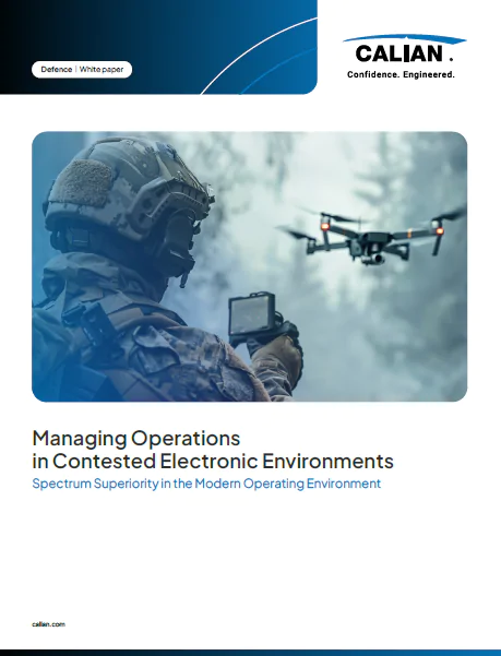 A soldier in tactical gear operates a handheld device while monitoring a drone in flight, highlighting electronic operations in a defense context.