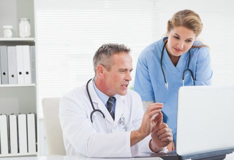 Two doctors looking at a laptop in an office.