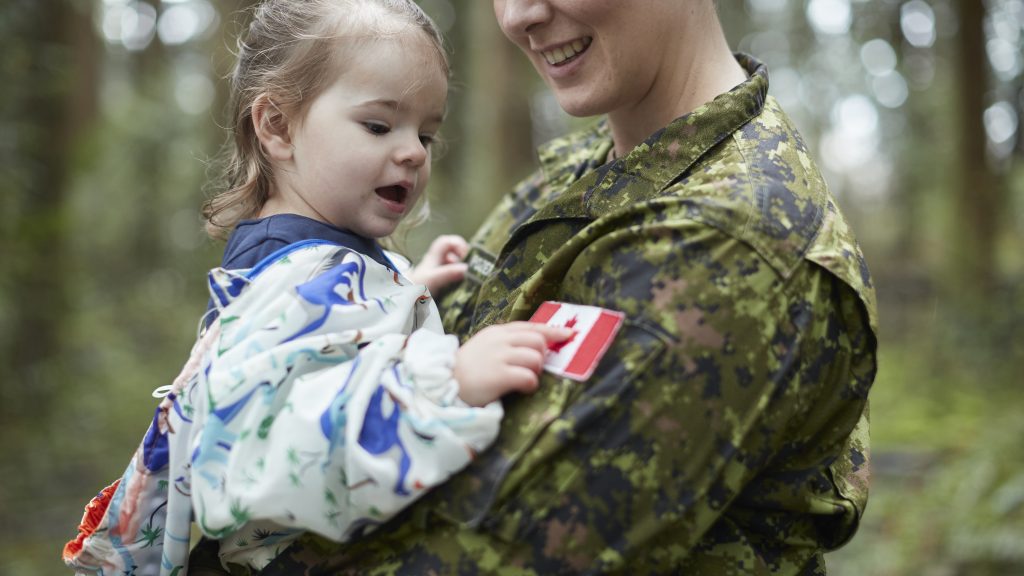 A woman in a military uniform holding a child.