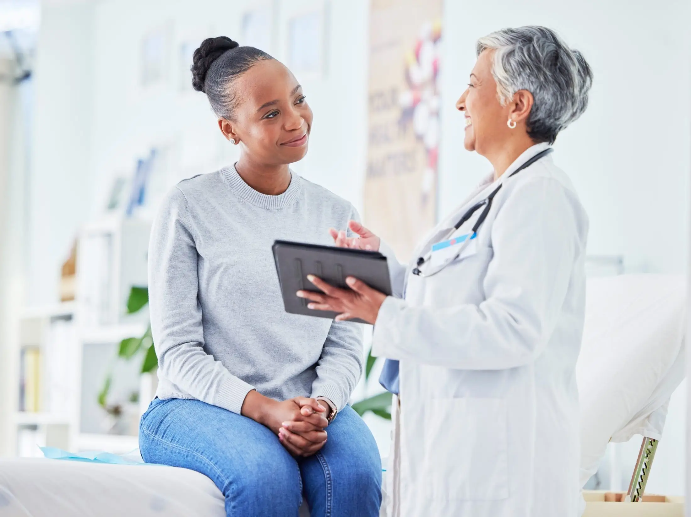 A female doctor is talking to a patient on a bed.