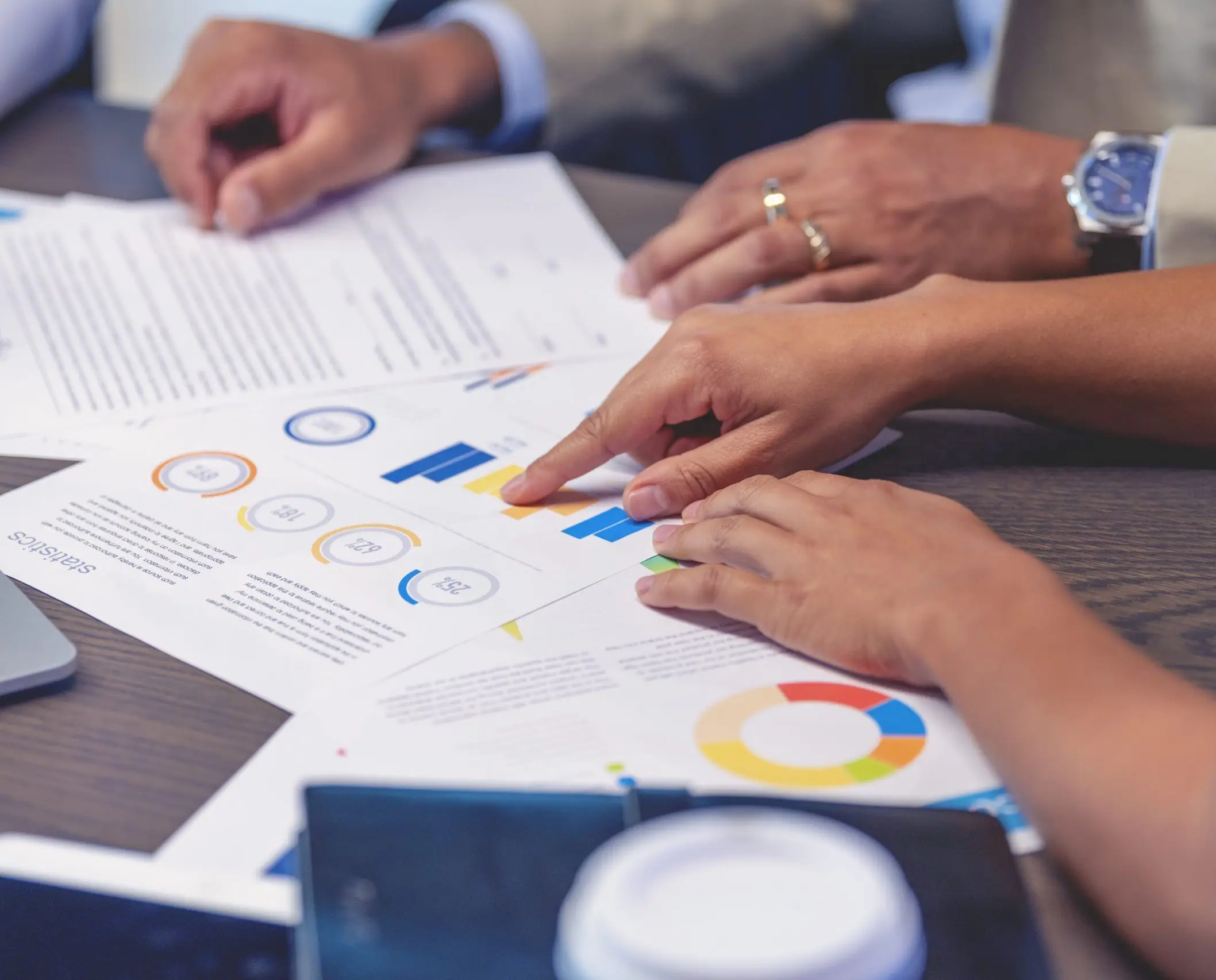 A group of business people pointing at graphs on a table.