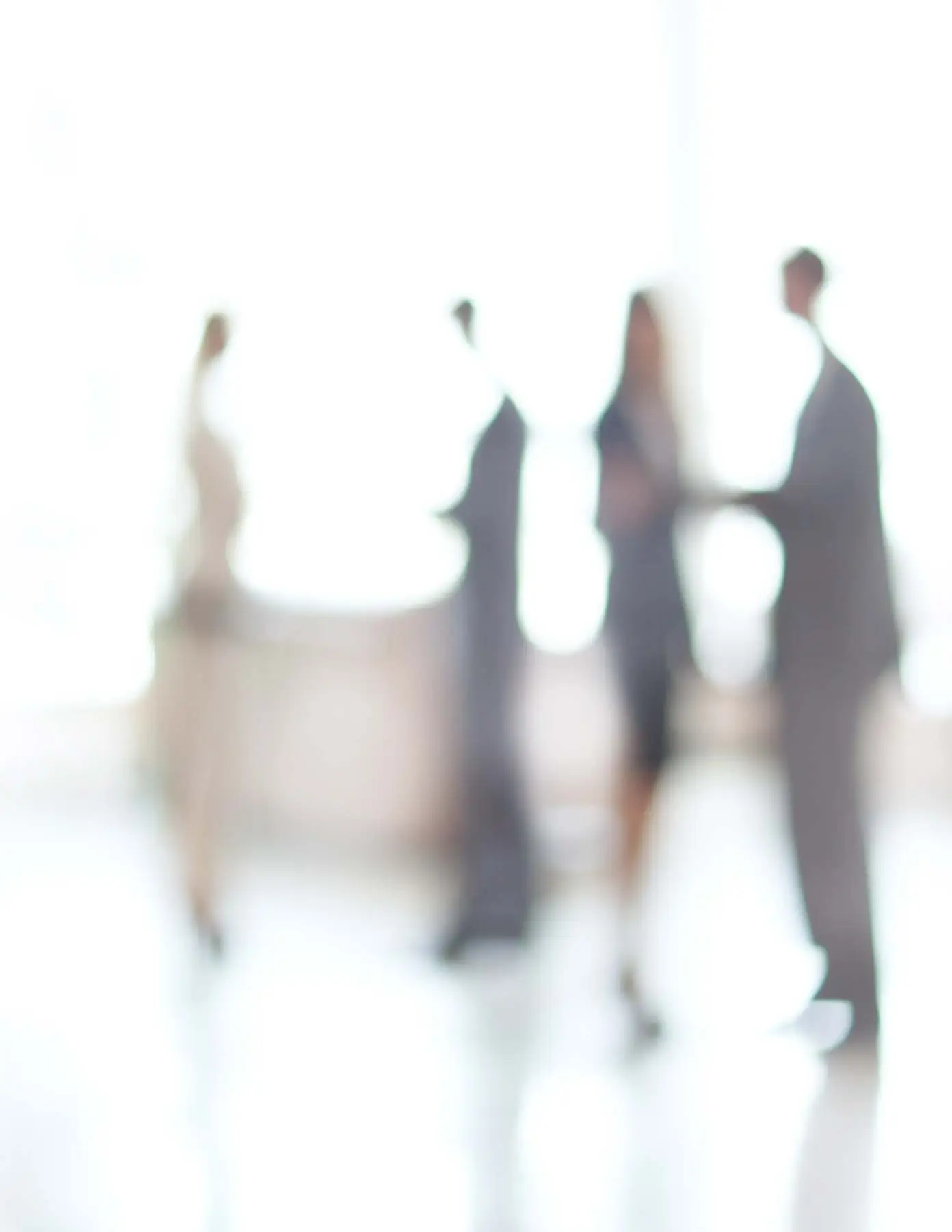 Blurred image of several people standing in a well-lit room.