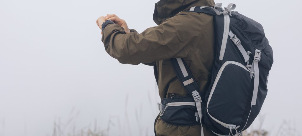 Woman hiker checking the altitude on her smartwatch at foggy mountain top