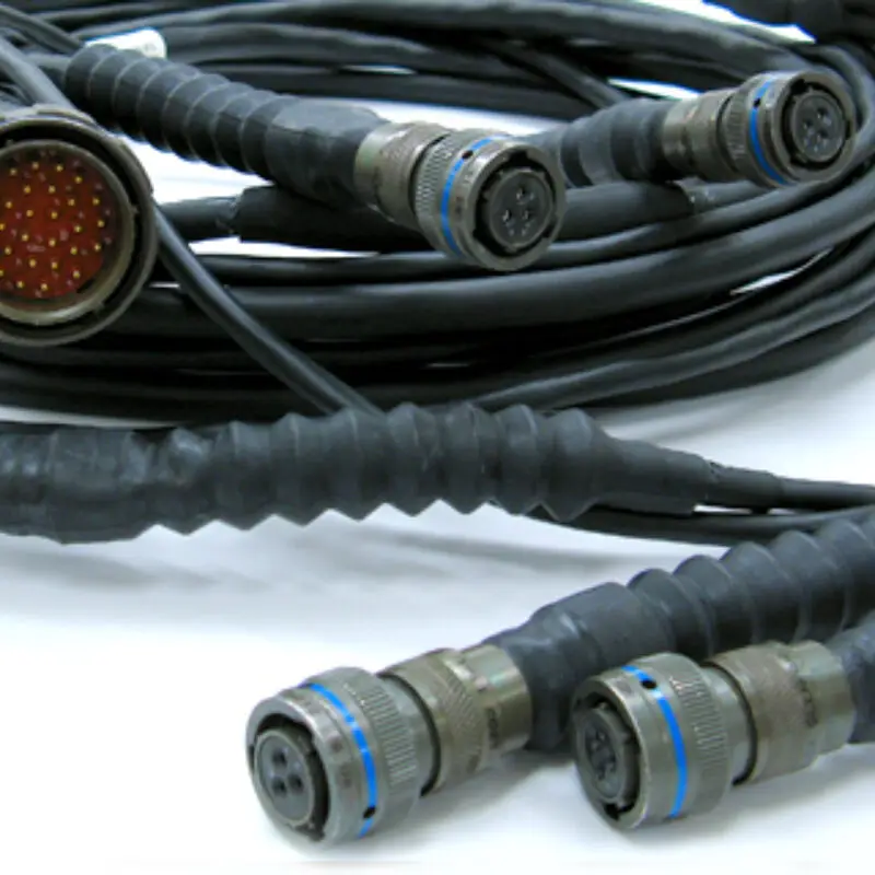 Close-up of various types of industrial cables with circular multi-pin connectors, arranged on a white background.