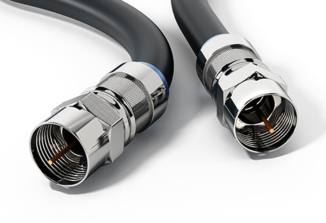 Two coaxial cables with metal connectors extending from a black cable sleeve, lying on a white surface.