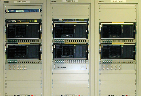 Rangée de trois racks de serveurs industriels remplis de divers équipements de réseau et de câbles dans un centre de données.