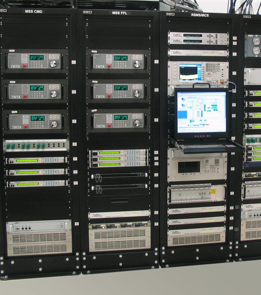 A rack of sophisticated electronic equipment with various modules and a monitor displaying graphs, used for telecommunications or computing.