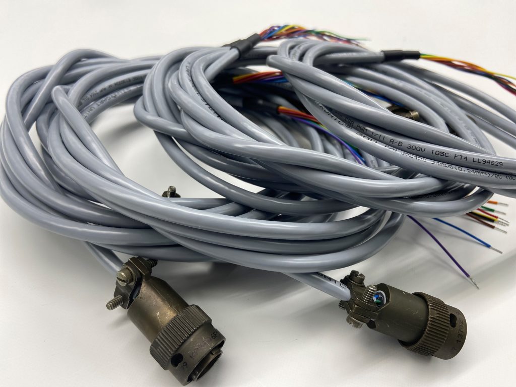 Coiled gray cables with multiple colored wires protruding from one end and connectors attached at the other.