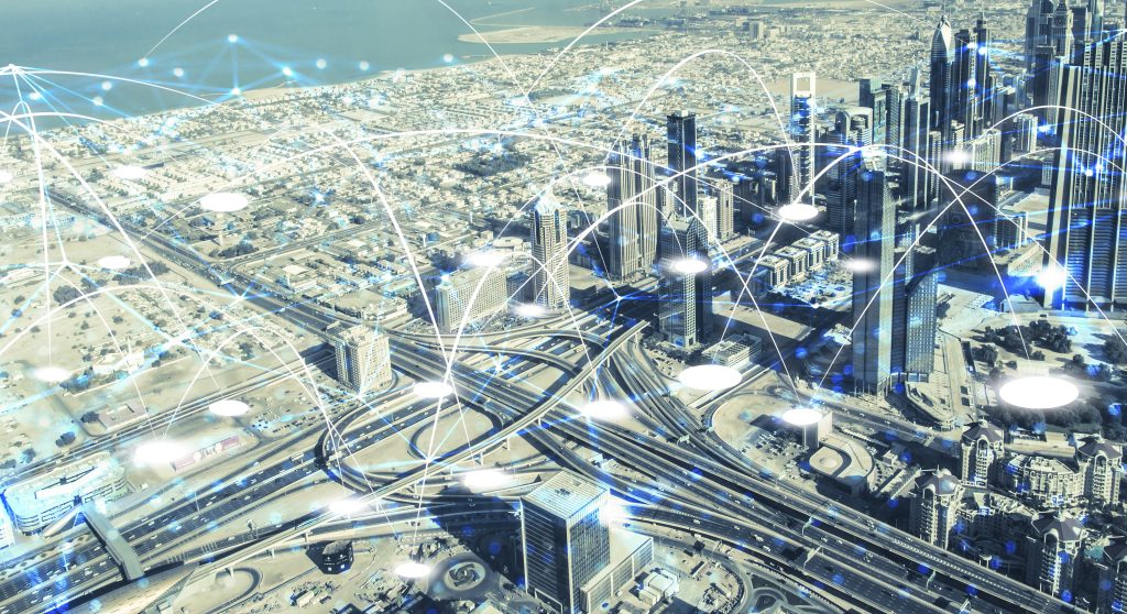 Vue aérienne d'une ville de nuit avec des rues et des bâtiments illuminés, superposés à des lignes lumineuses représentant la connectivité numérique.