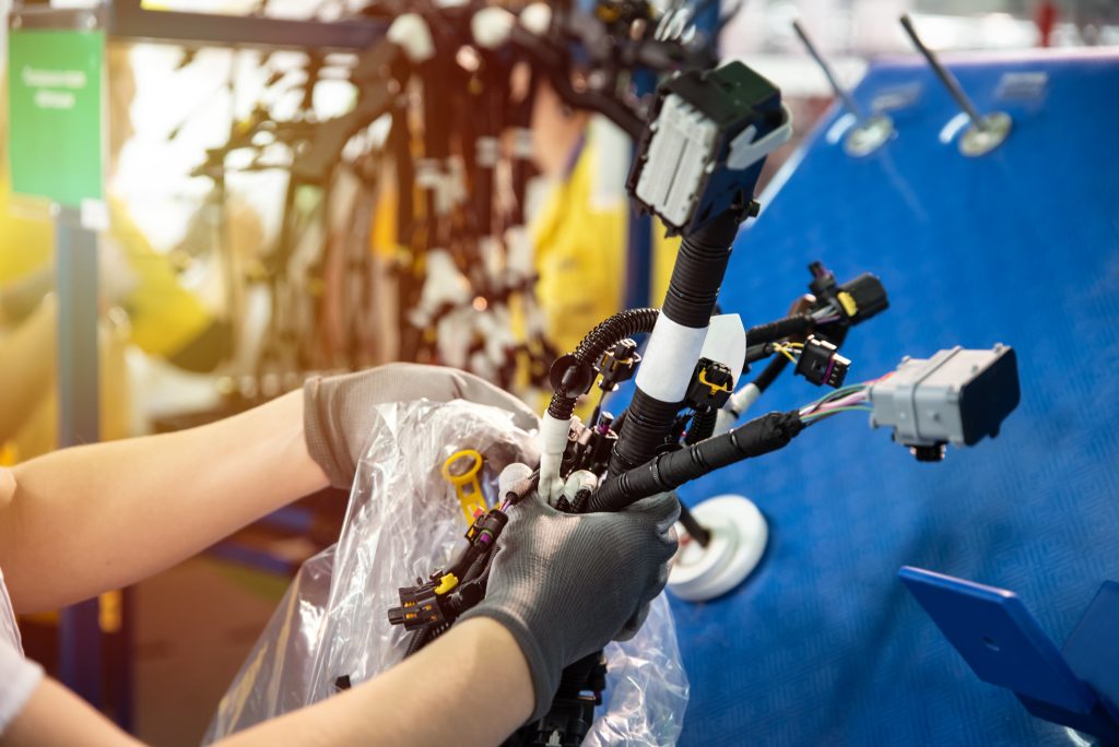 Hands of a technician in gloves assembling complex robotics parts in an industrial setting.