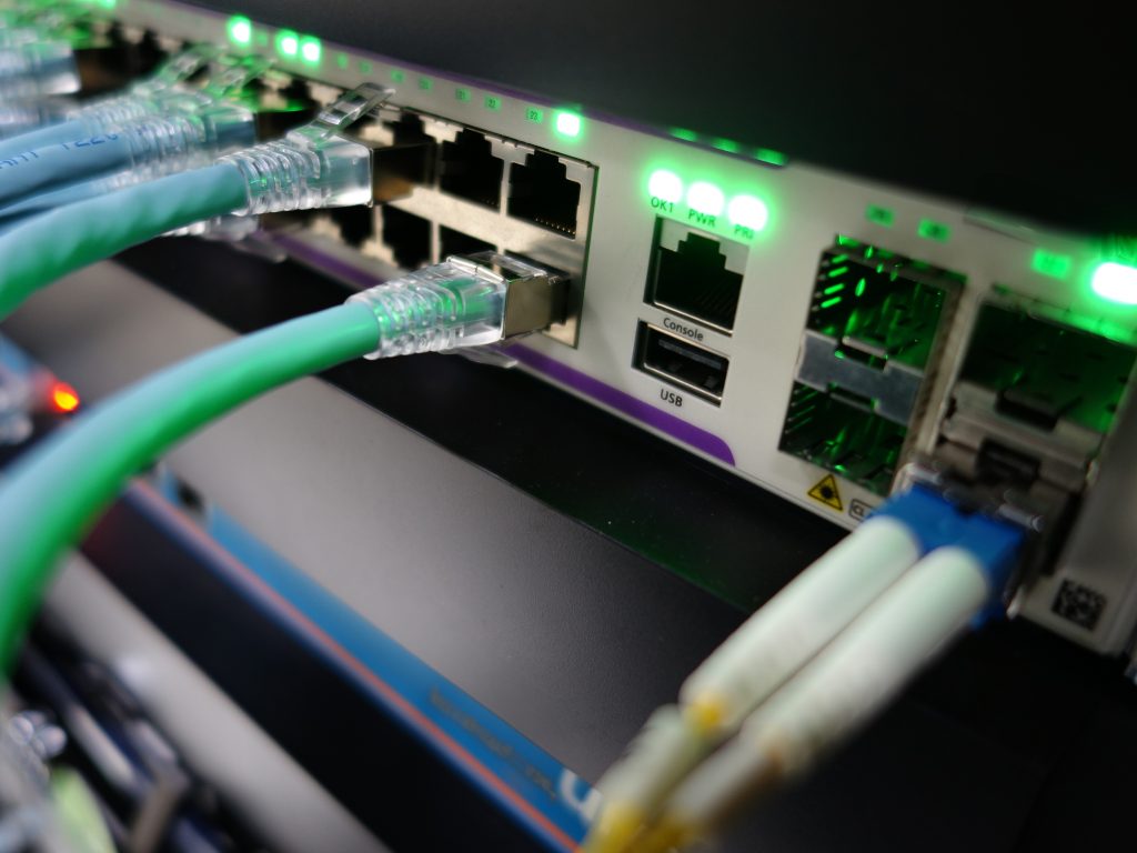 Ethernet cables connected to a network switch with glowing green indicator lights, showing active data transmission.