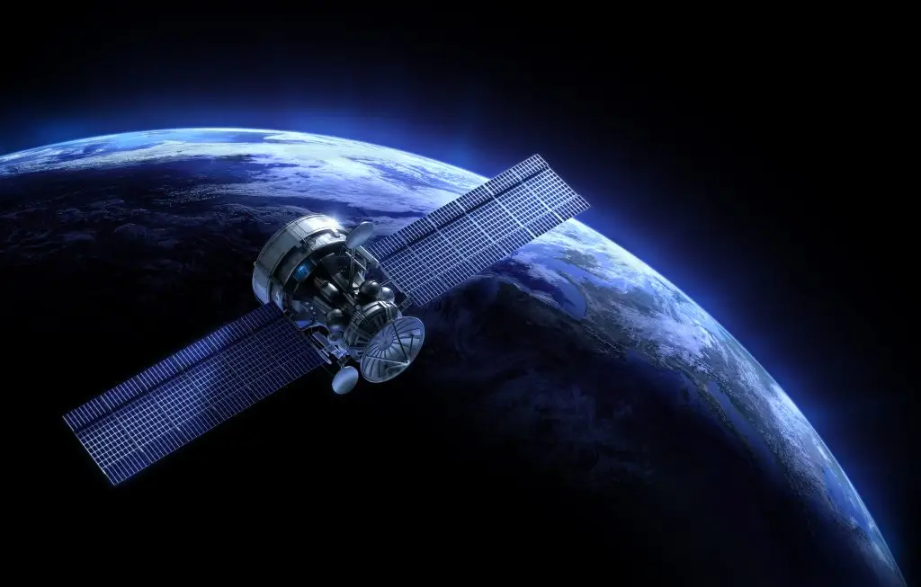 A satellite with large solar panels orbits above Earth, visible against the backdrop of space.
