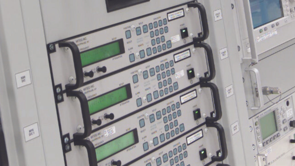 A rack of electronic equipment with multiple control panels featuring buttons, knobs, and digital displays.