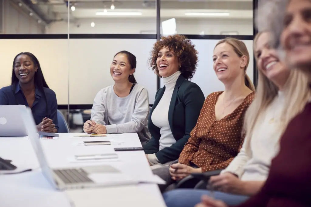 Un groupe de femmes assises autour d'une table et riant.