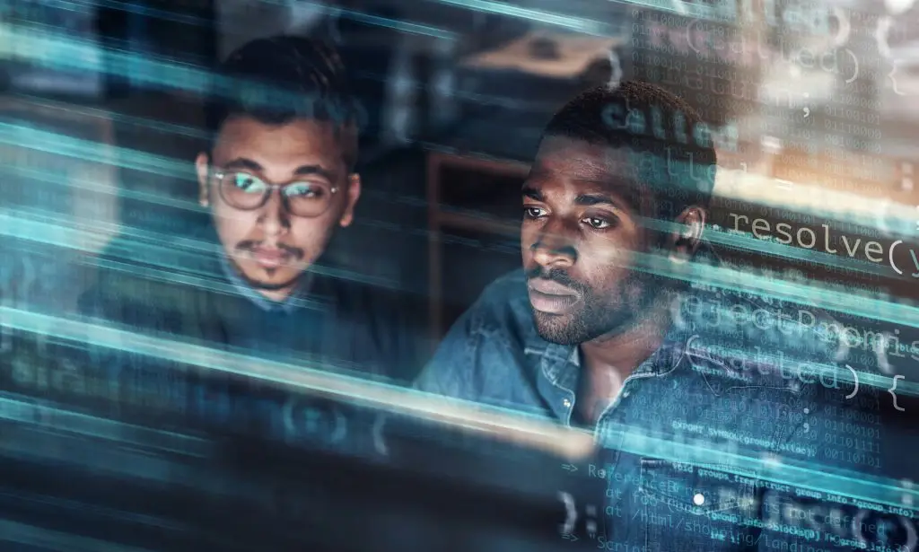 Two software developers focused on coding, with screen reflections overlaying their intense expressions.