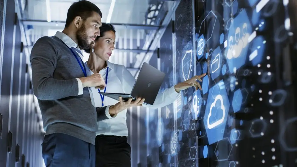 Two professionals analyzing data in a server room.