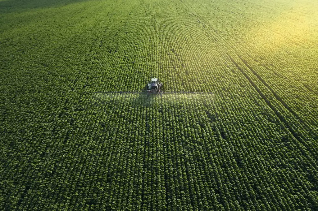 An aerial view of a tractor spraying a field.