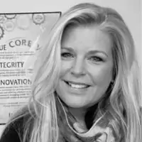 A person with long hair smiling, wearing a scarf. A poster with the words "Core," "Integrity," and "Innovation" is partially visible in the background.