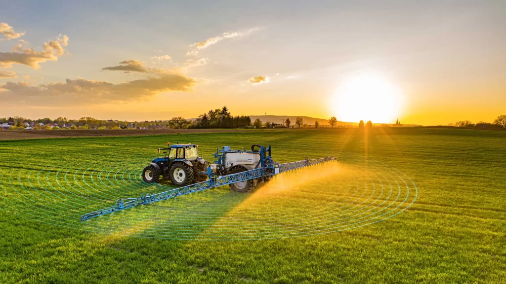 A tractor sprays crops in a green field at sunrise, with digital overlay lines indicating precision agriculture technology.